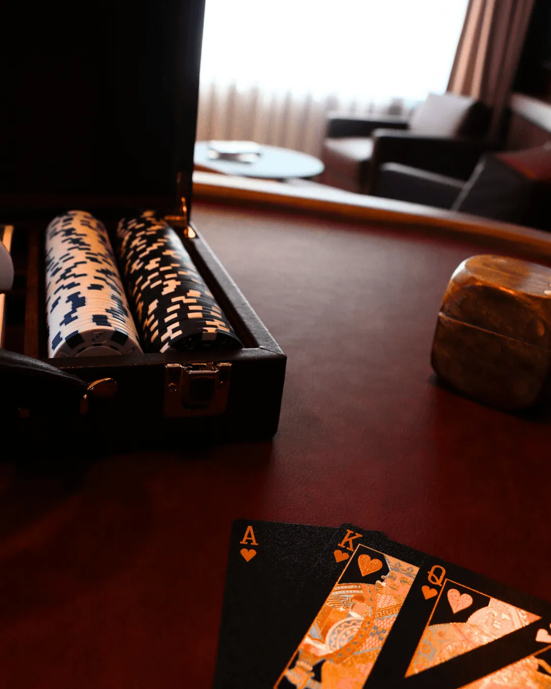 Un étui ouvert contenant des jetons de poker, des cartes à jouer posées sur une table et un fond flou avec des canapés