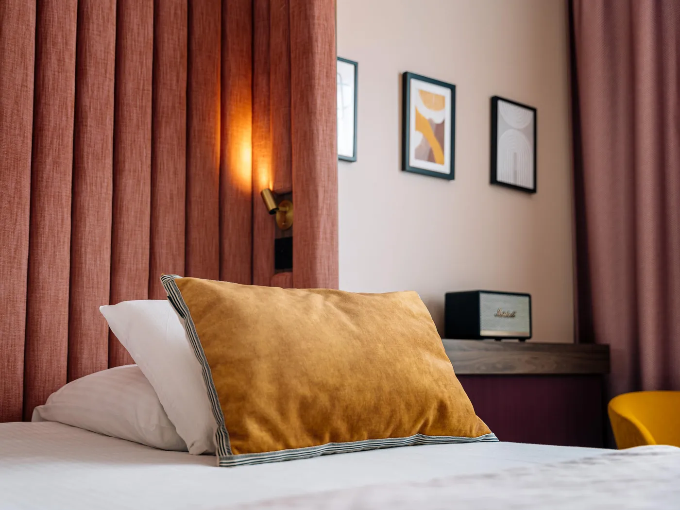 Lit avec des coussins, une lampe allumée et des cadres sur le mur