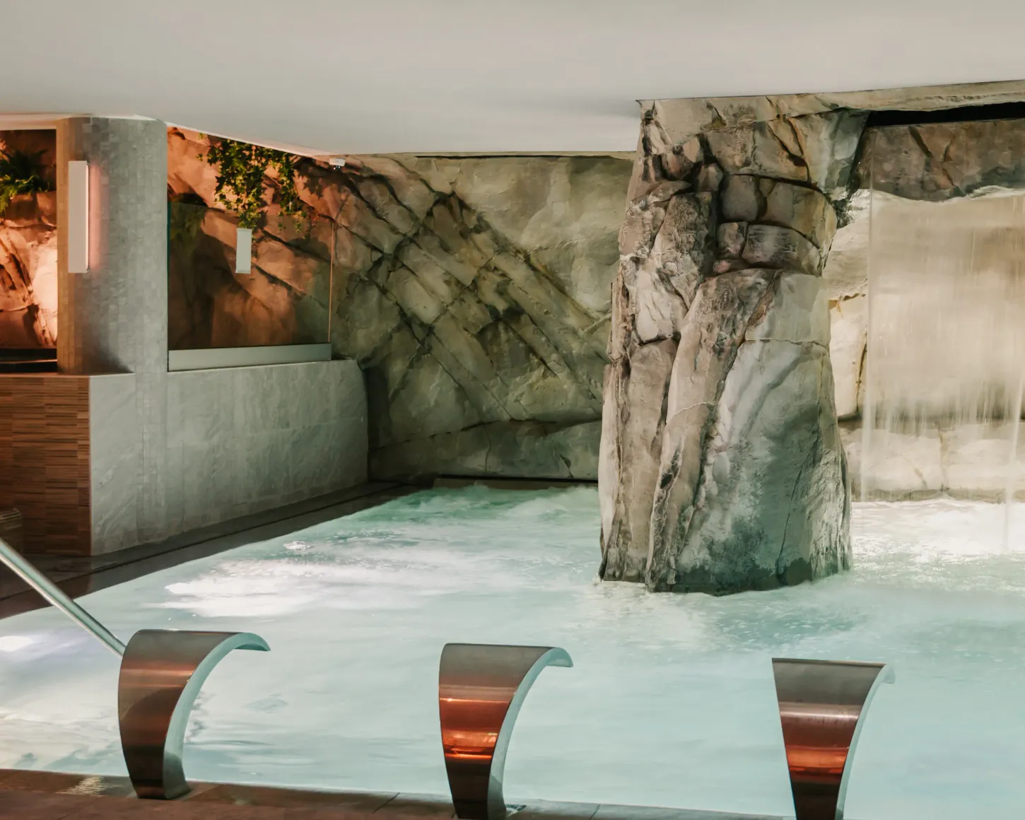 Indoor pool with decorative rocks and partially submerged metal seats