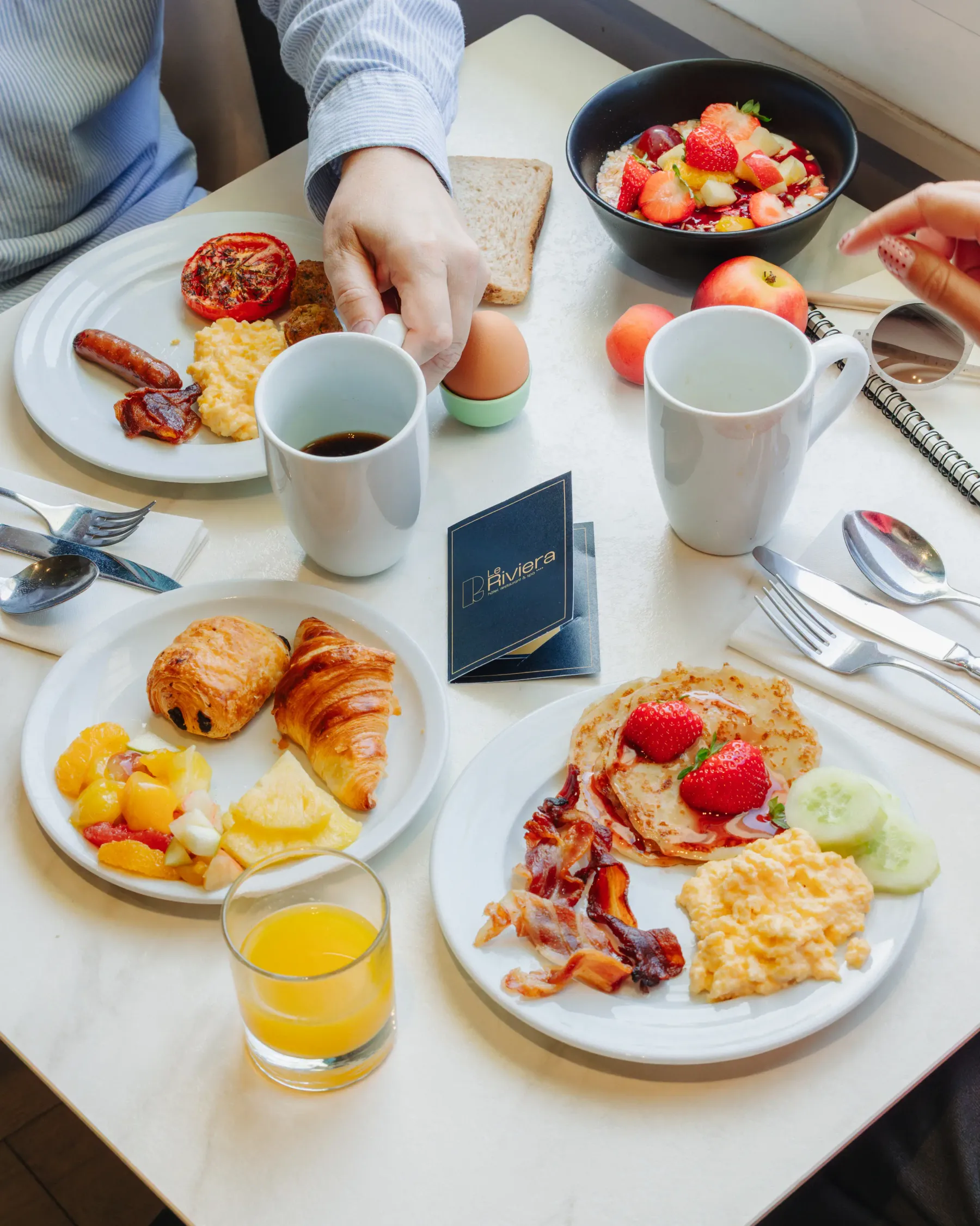 Table de petit-déjeuner avec des plats variés, des boissons et des couverts, vue de dessus