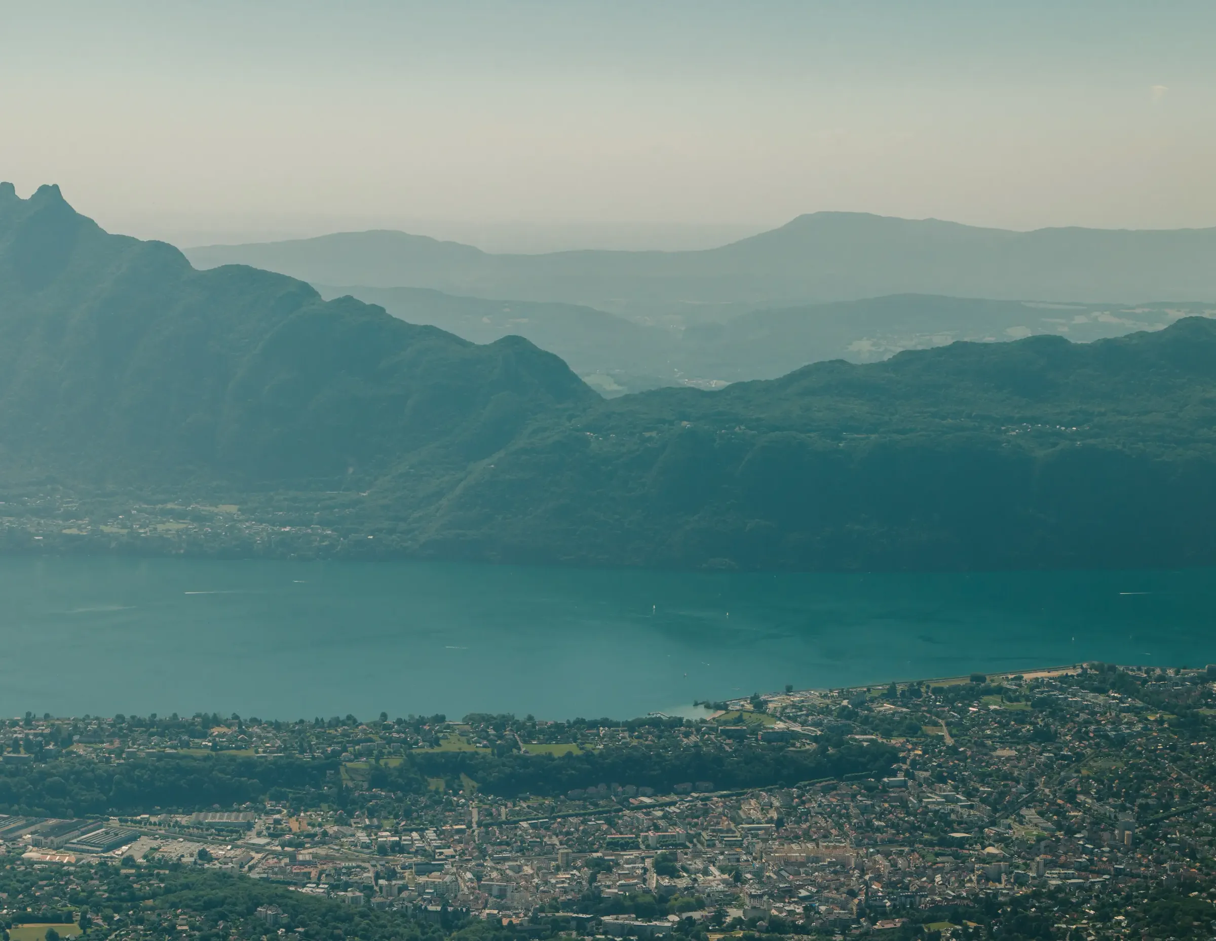 Stadt, die von einem von Bergen umgebenen See mit vielfältigem Relief und dichter Vegetation gesäumt ist