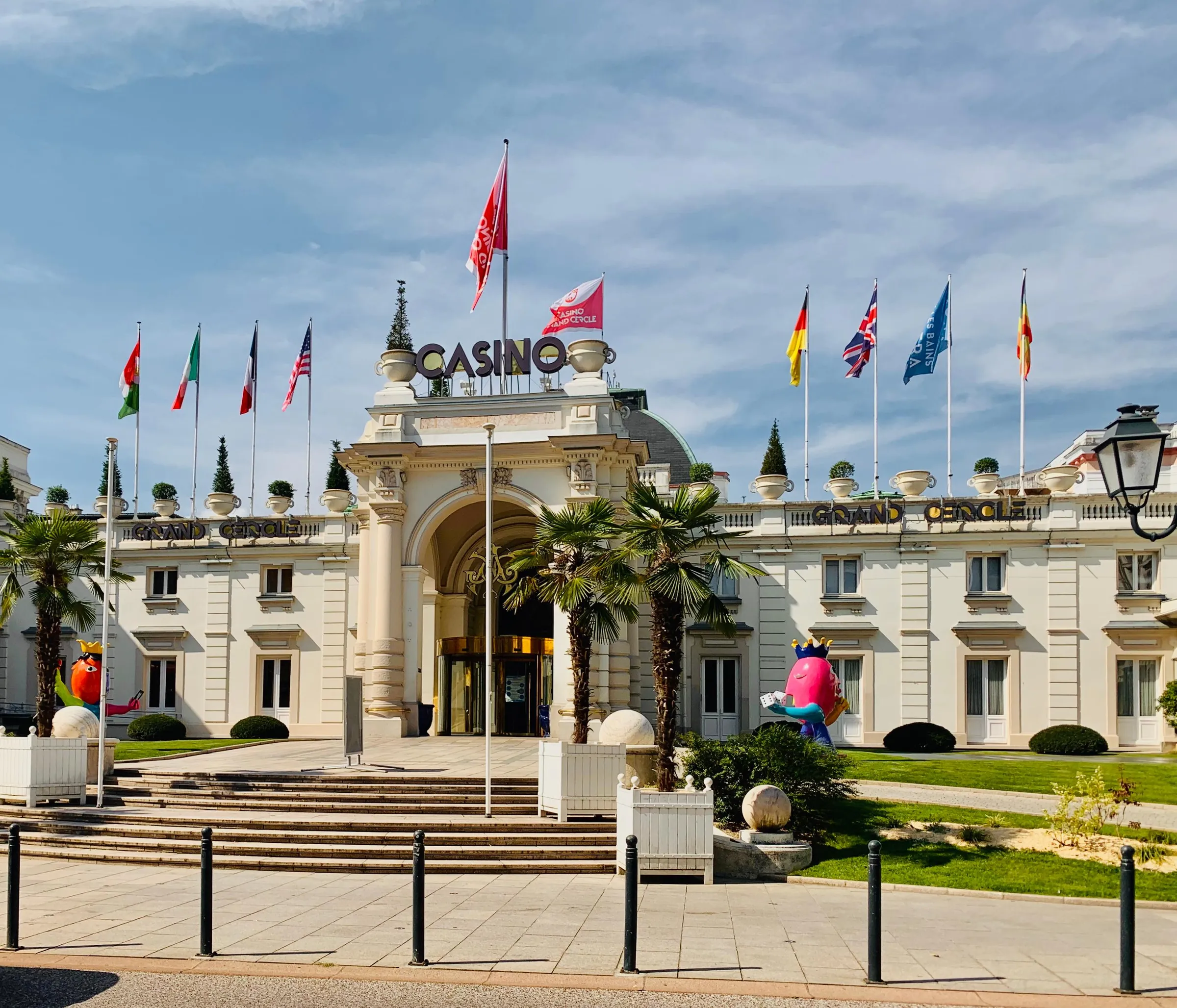 Grand bâtiment blanc avec l'enseigne "CASINO" et plusieurs drapeaux devant l'entrée principale