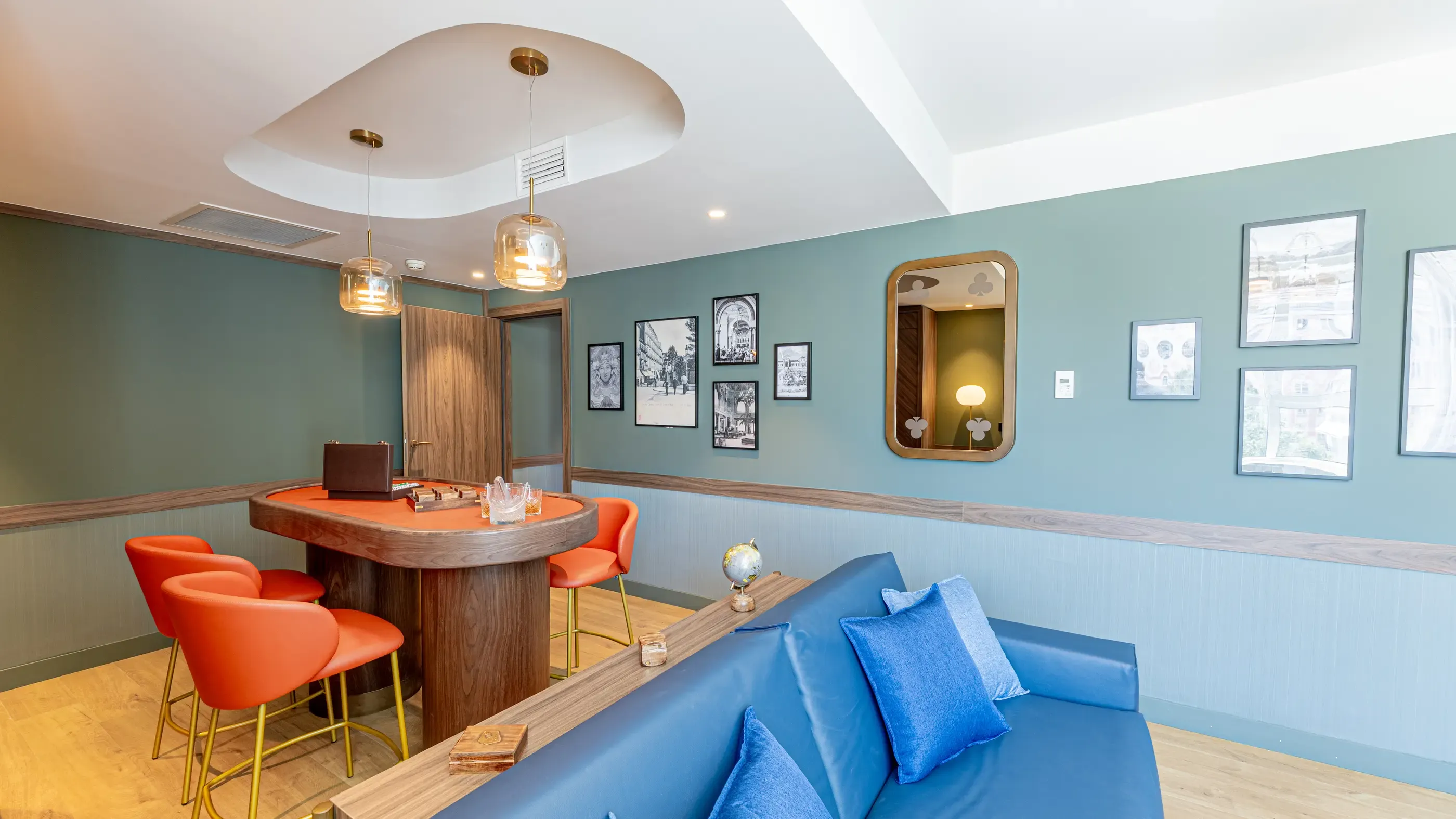 Salle avec un canapé bleu, des chaises rouges autour d'une table et des œuvres d'art encadrées sur les murs