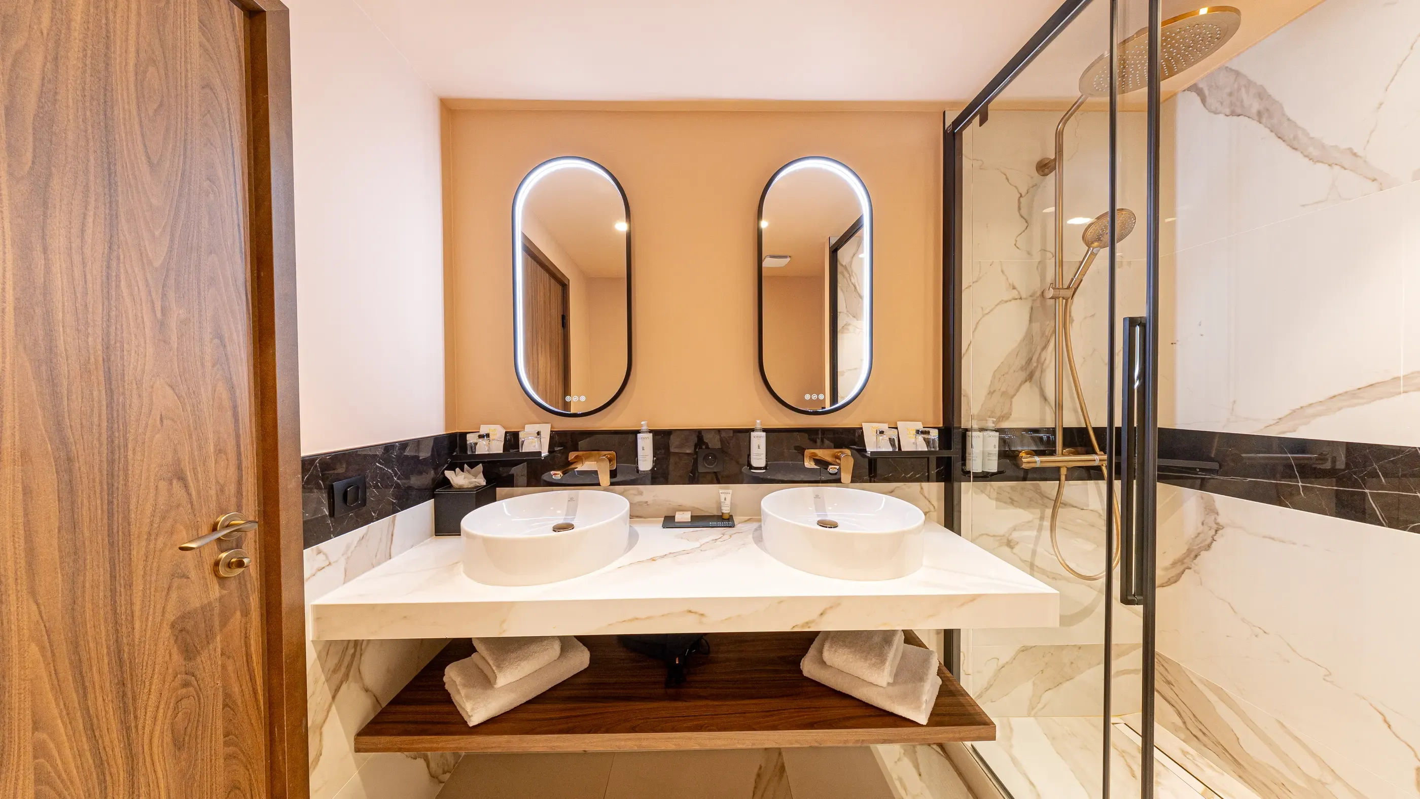 Moderne Badezimmer mit Doppelwaschbecken, ovalem Spiegel und Glastür-Dusche