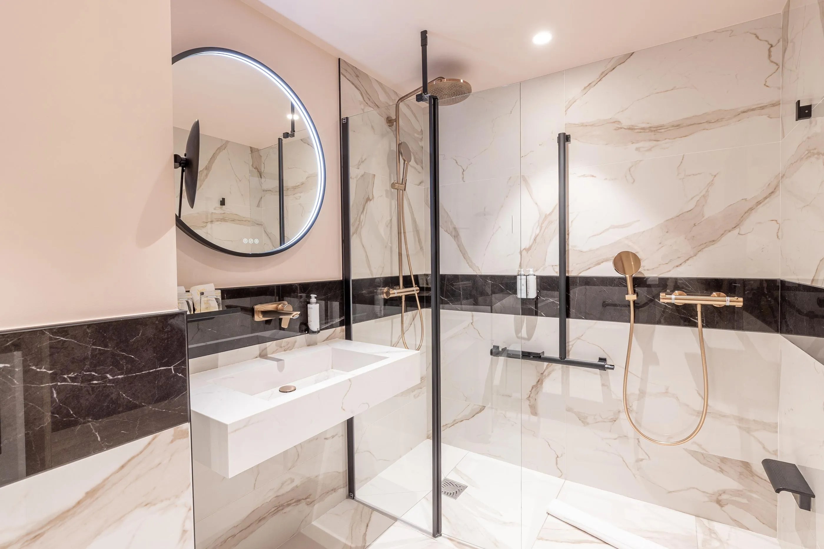 Modern bathroom with rain shower, white sink, and round mirror framed in black