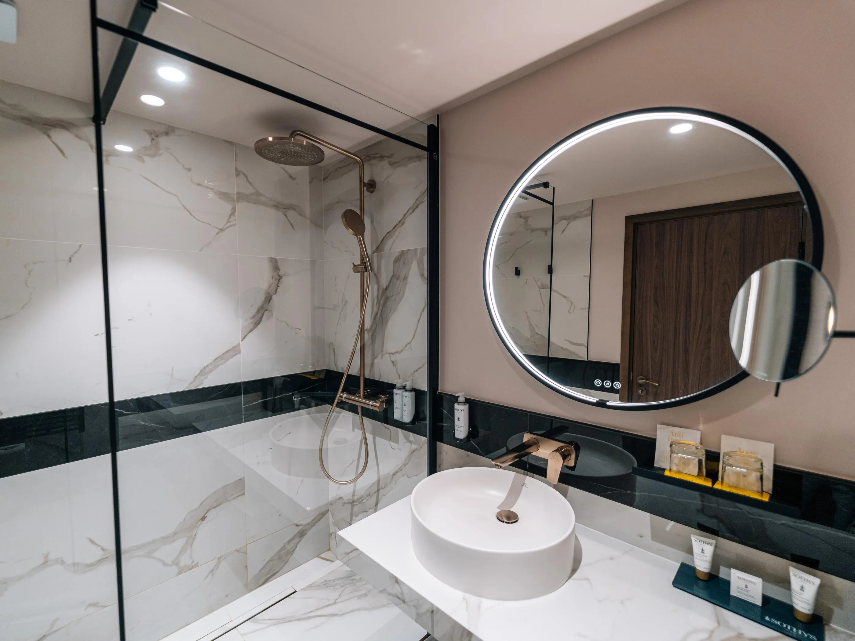 Moderne Badezimmer mit Dusche, Waschbecken und runden Spiegeln auf weiß-schwarzem Marmorboden