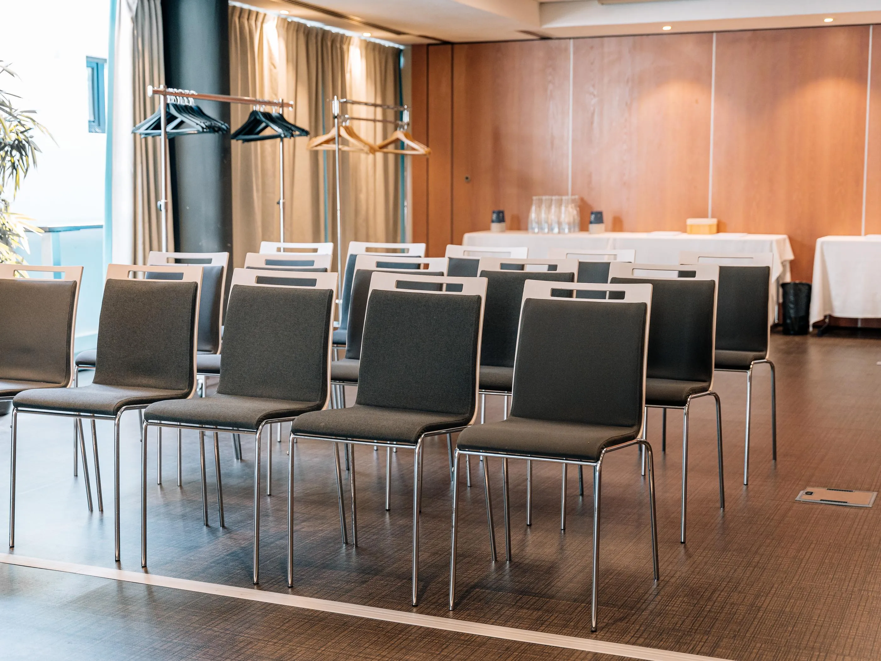 Salle de réunion avec des rangées de chaises et des tables recouvertes de nappes blanches en arrière-plan