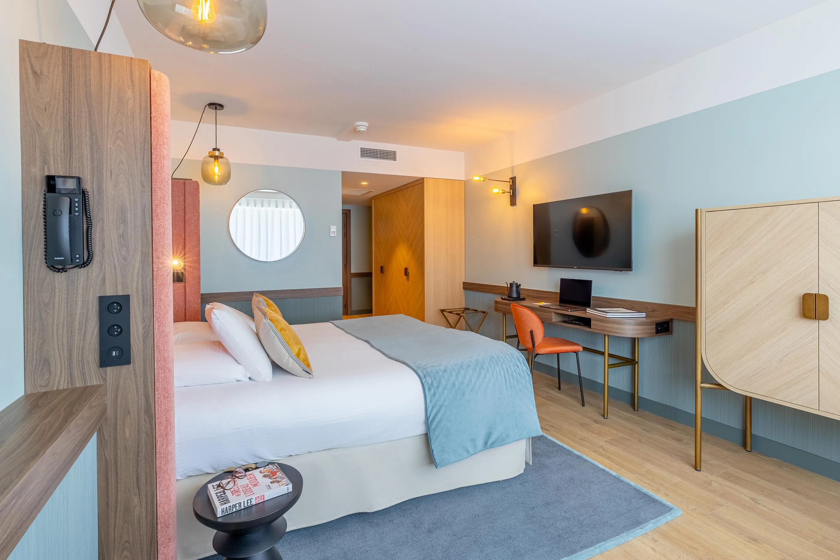 Moderne Hotelzimmer mit Bett, Schreibtisch, Fernseher und Holzelementen sowie Metall