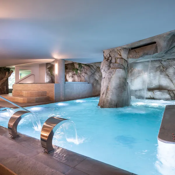Piscine intérieure avec cascades et rochers artificiels, éclairée par une lumière naturelle tamisée