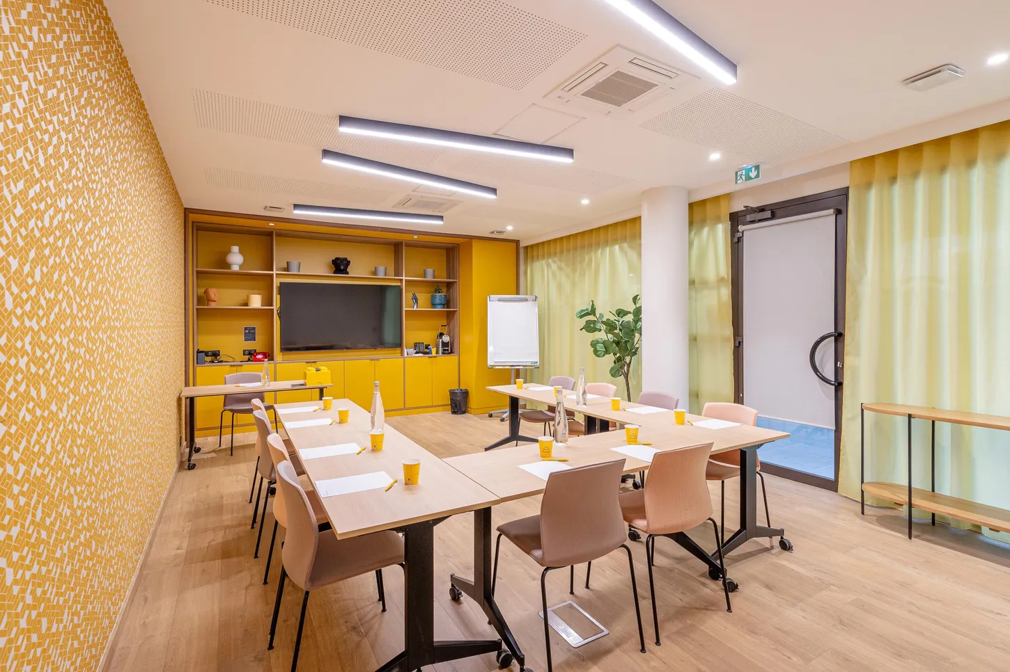 Meeting room with tables, chairs, screen, projector, and yellow wall decoration