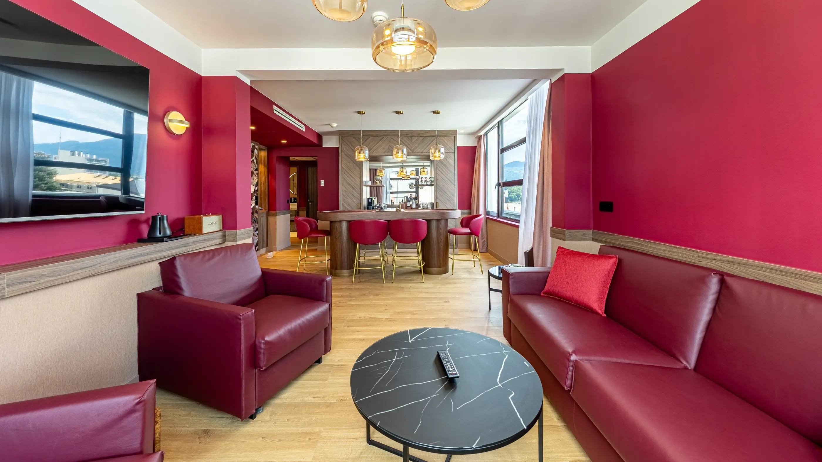 Lounge with red leather sofas and armchairs, black coffee table, bar with stools and panoramic view
