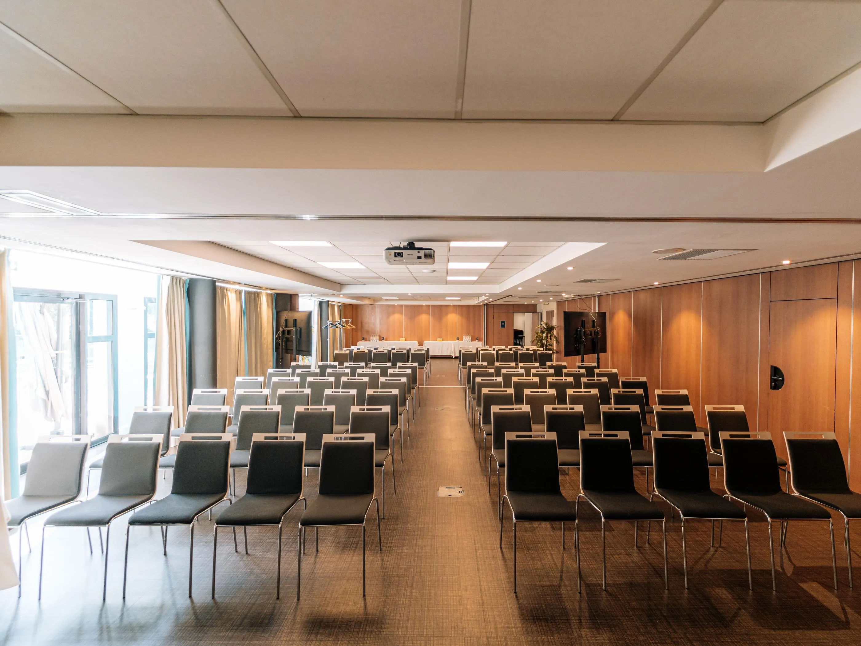 Konferenzraum mit Reihen von aufgestellten Stühlen und einem Deckenprojektor