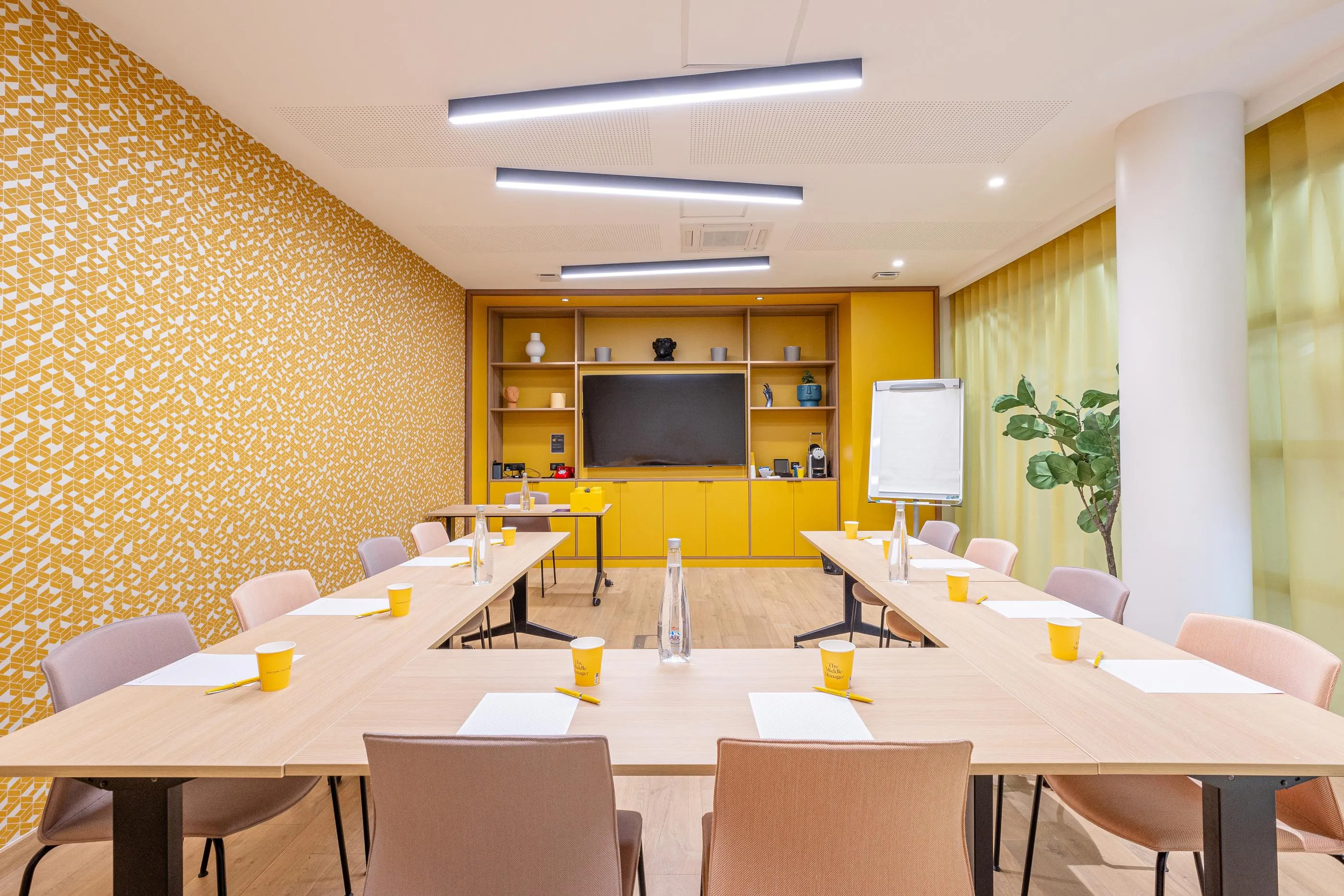 Meeting room with tables, chairs, screen, whiteboard, wall decoration, and plants