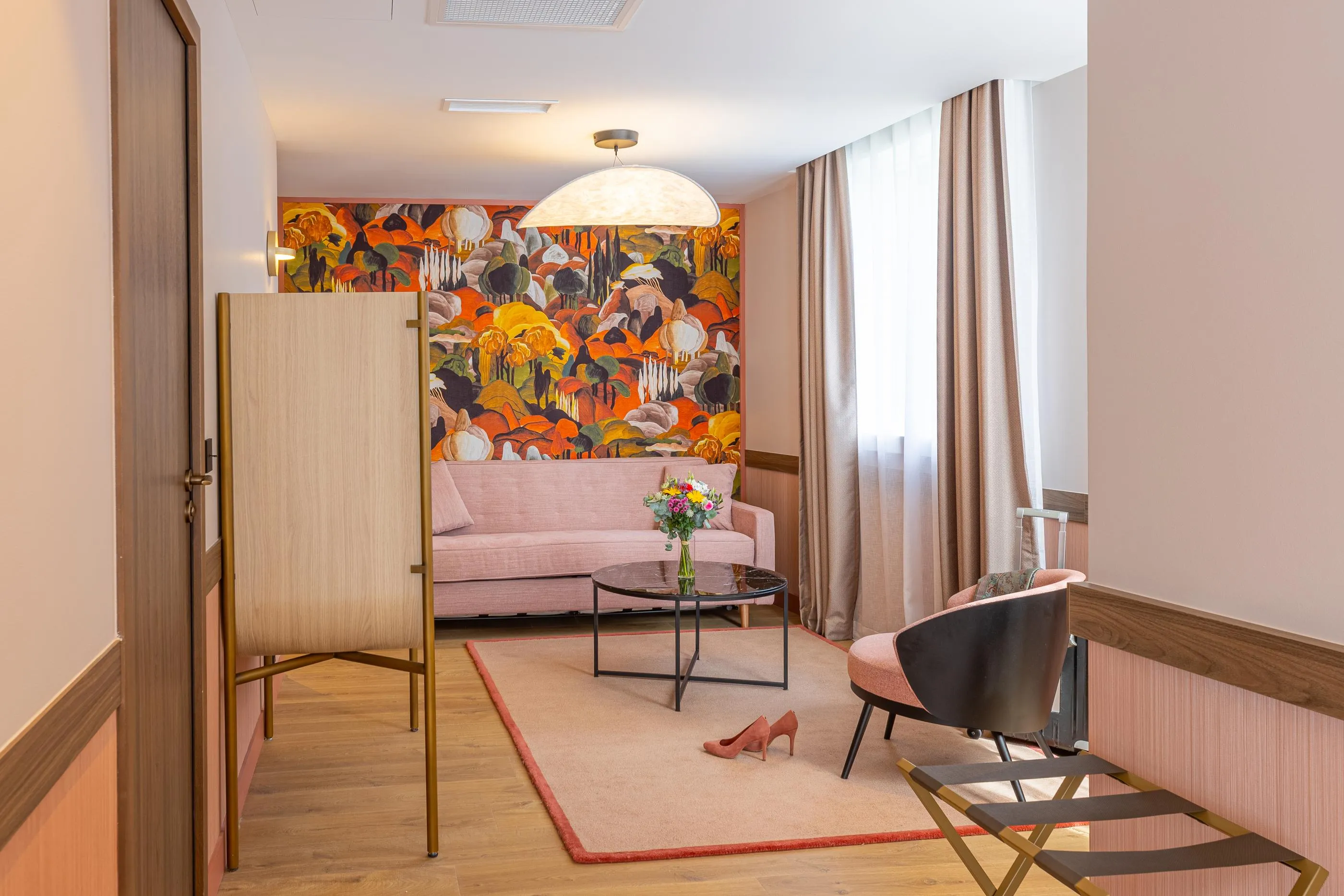 Wohnzimmer mit beigem Sofa, Sessel, Couchtisch, Paravent und einem Paar rosafarbener Schuhe auf dem Teppich